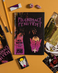 Books titled 'Pilgrimage of the Penitent' by Nick Rider and Mark Foss on a yellow background with pencils and cards.
