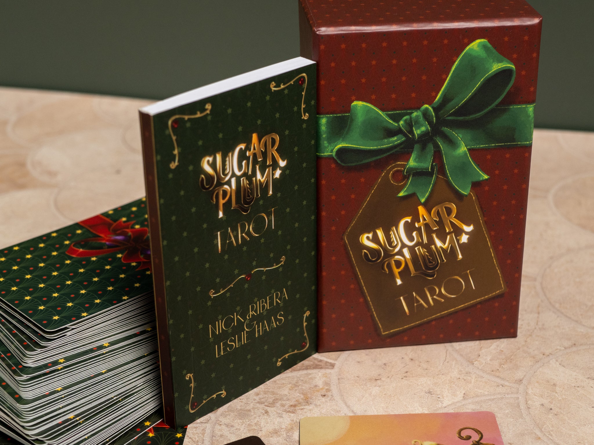 Sugar Plum Tarot book and packaging with a green ribbon on a textured surface