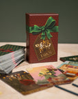 Card game with a red box featuring a green bow and 'A Sugar Plum Carol' text on a wooden surface.